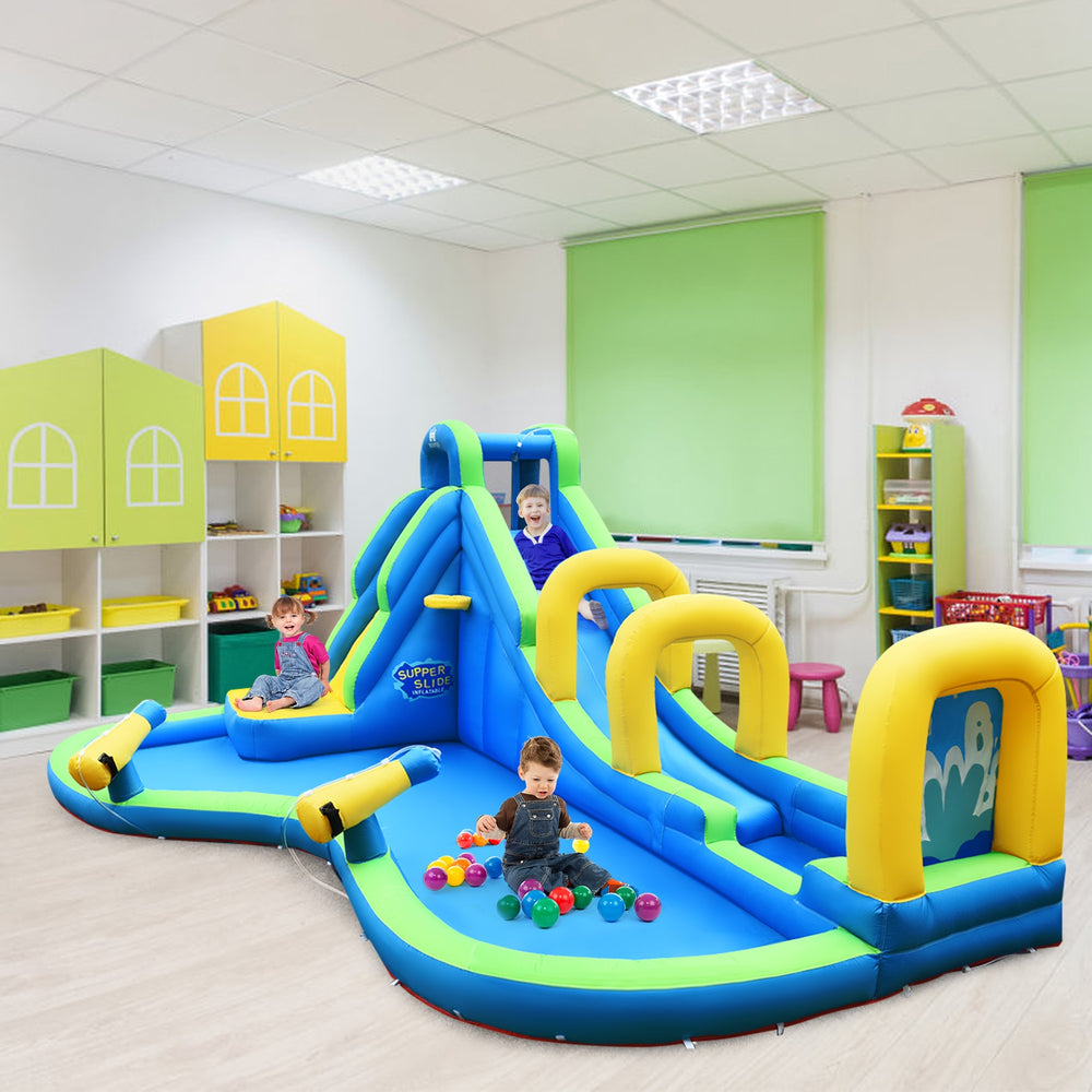 Inflatable water slide bounce house with climbing wall, splash pool, and water cannons for kids' fun indoors.