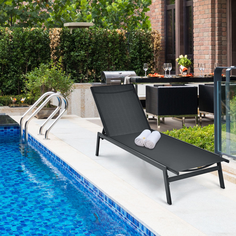 Black outdoor reclining chaise lounge chair by the poolside, featuring a 6-position adjustable backrest for comfort.