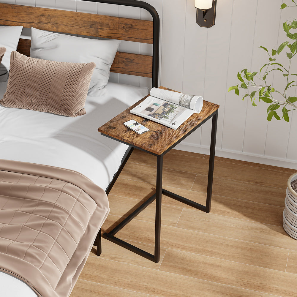 C-shaped industrial end table with a wood grain finish, perfect for small spaces and multifunctional use beside a bed.