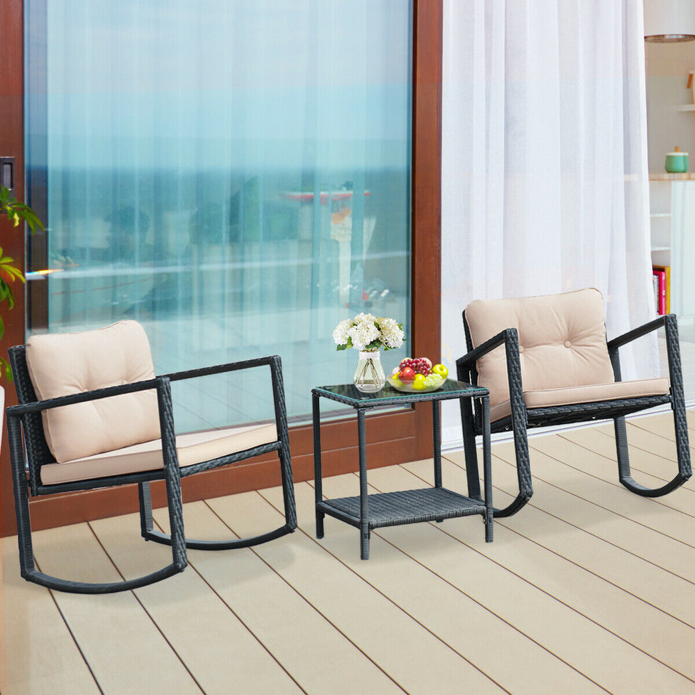 Two beige rocking chairs with cushions and a glass-top coffee table in a wicker bistro set for outdoor relaxation.