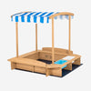 Kids wooden sandbox with striped canopy, featuring cedar wood, seating, and plastic bins for sand and water play.