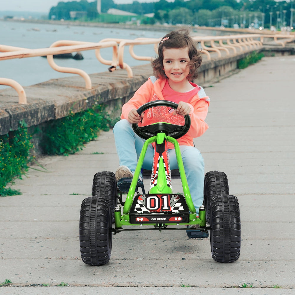 Child enjoying a green 4 wheel pedal powered ride-on with adjustable seat, navigating a path with non-slip wheels.