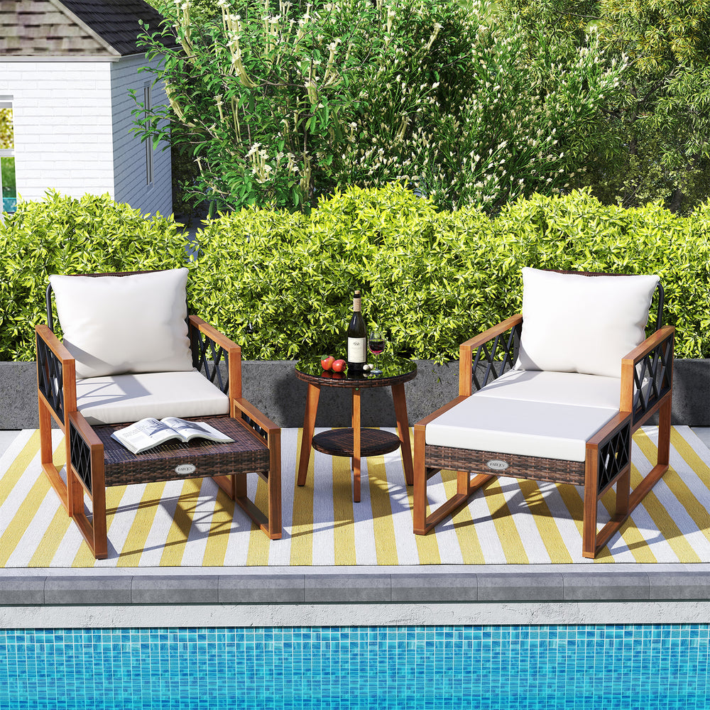 Outdoor patio furniture set featuring cushioned chairs and a glass-top table, made of PE rattan and acacia wood.