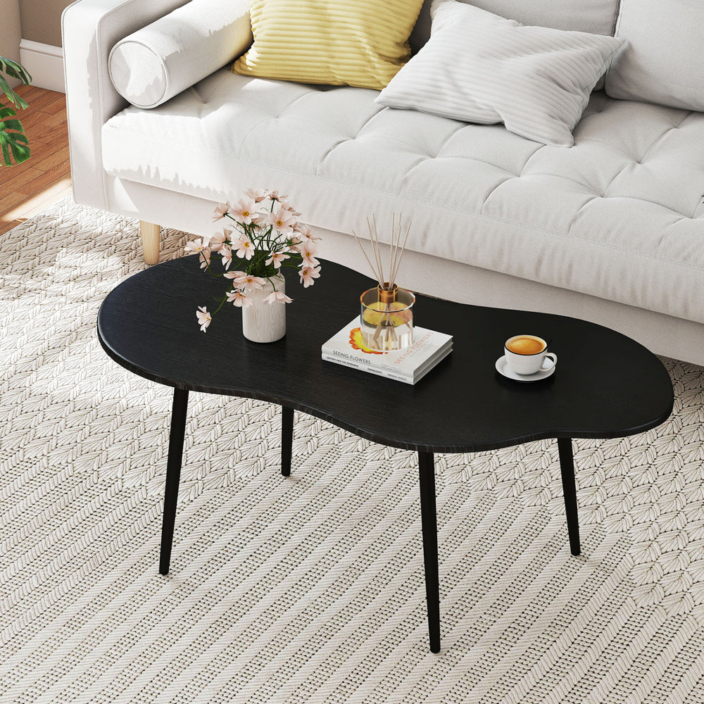 Cloud shape coffee table with a black metal frame, featuring a wide tabletop for living room organization and style.