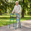Senior using a navy one-button folding aluminum walking frame walker in a park, designed for stability and mobility.