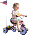 Toddler riding the Glowing Wheels Tricycle with a basket, duck bell, and glowing wheels in a park setting.