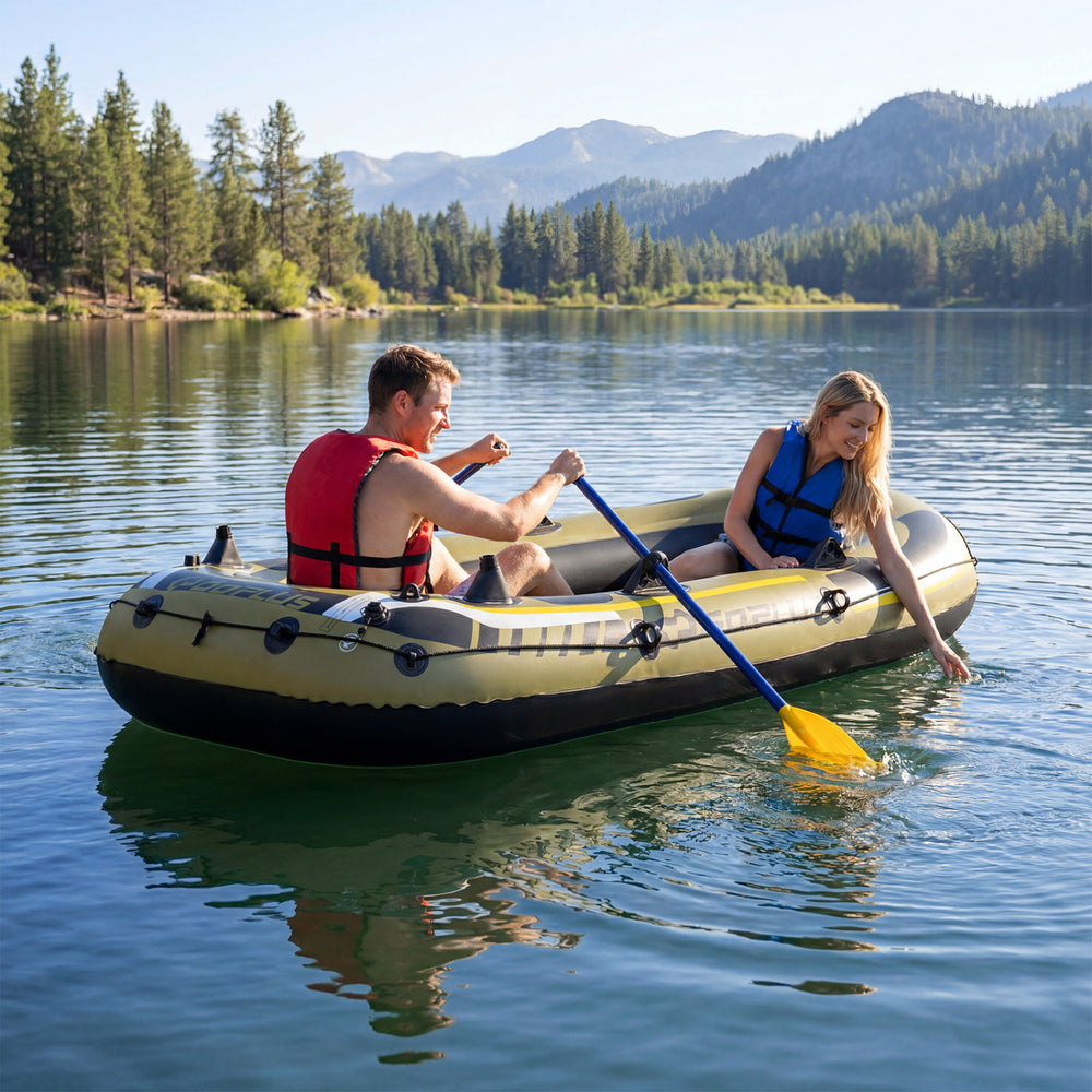 Three-person inflatable fishing raft in green, featuring paddlers on a lake with mountains in the background.