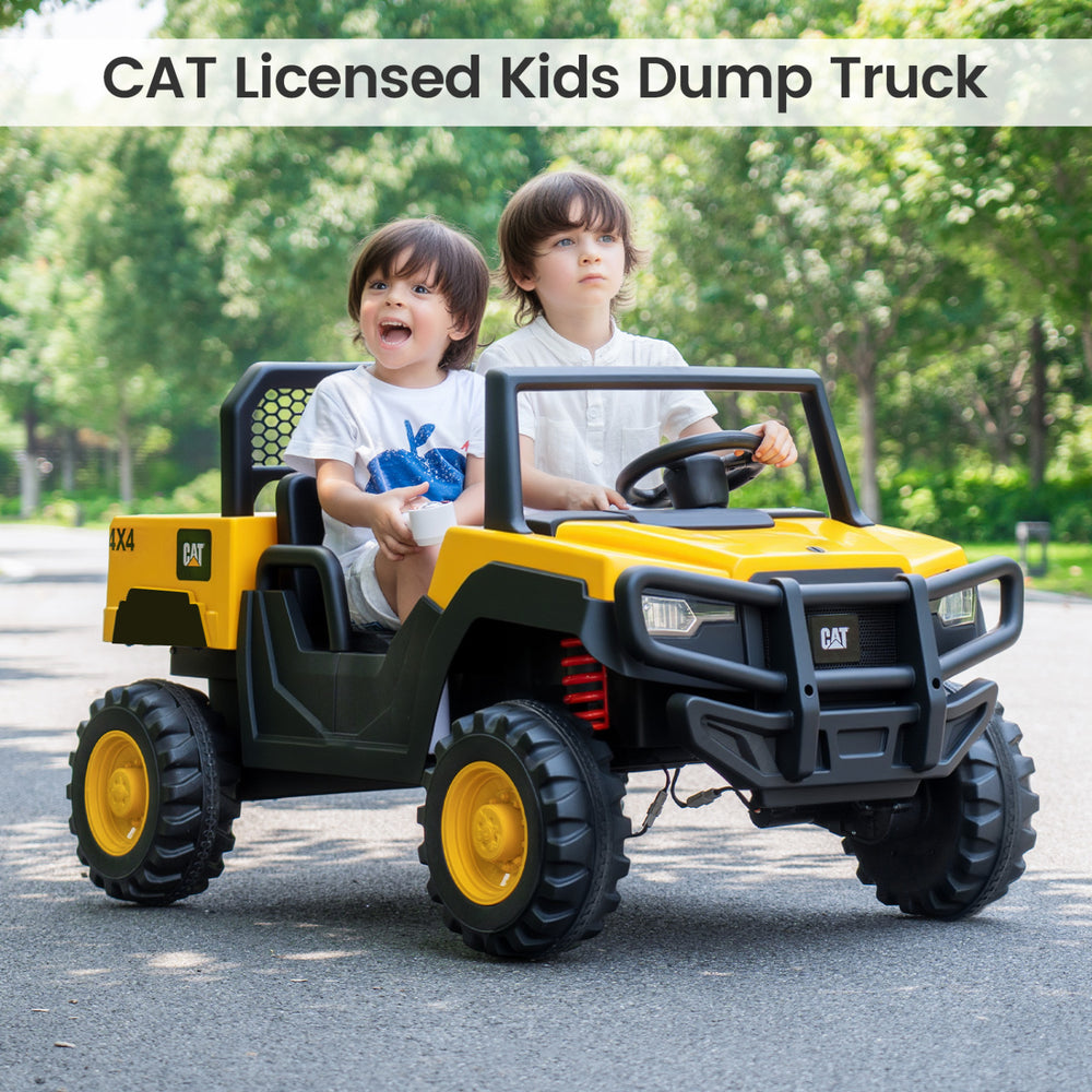 Two kids enjoying a ride in the yellow 24V licensed CAT dump truck, perfect for outdoor fun and adventure.