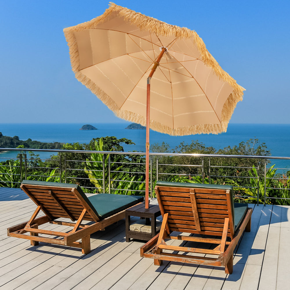 Two wooden lounge chairs with a 6.5 feet portable thatched tiki beach umbrella for outdoor relaxation by the sea.