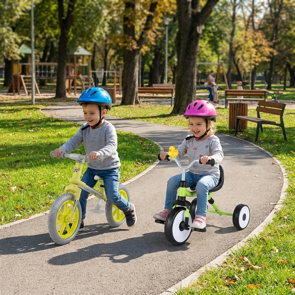 Two children riding a balance bike and tricycle from the 2-piece toddler bike set in a park, featuring glowing wheels and baskets.