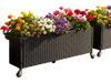 Raised garden bed made of fade-resistant PE rattan with vibrant flowers, featuring wheels for easy mobility in outdoor spaces.