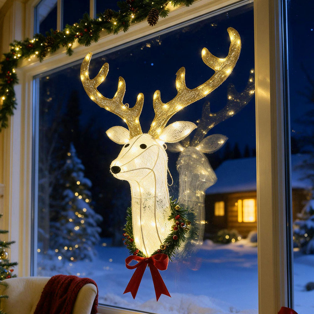 3D Rudolph hanging wreath with glowing LED lights, tinsel fabric, and red bow displayed in a festive window scene.