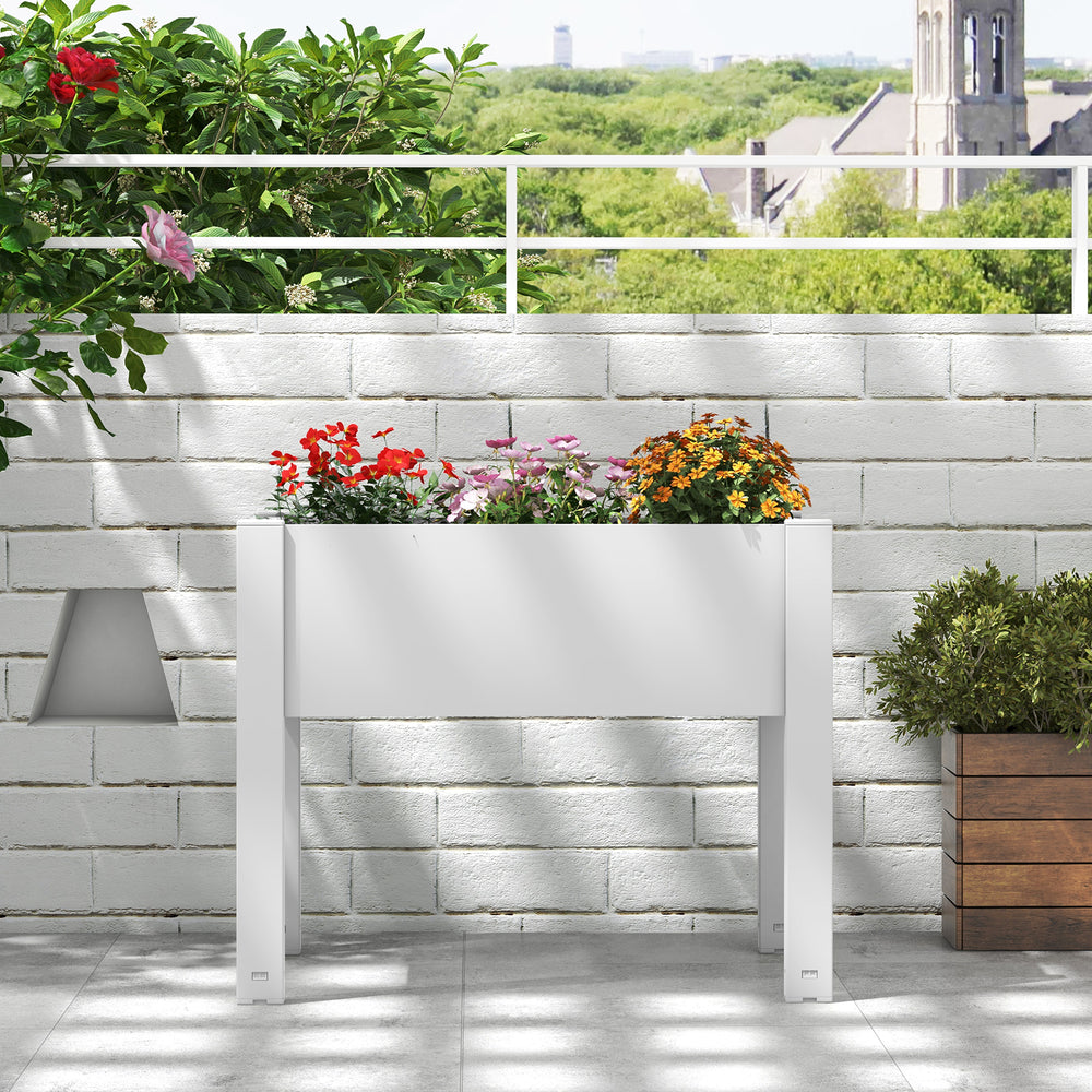 Self-watering raised bed planter box in white with flowers, ideal for garden or patio use, featuring a water level.